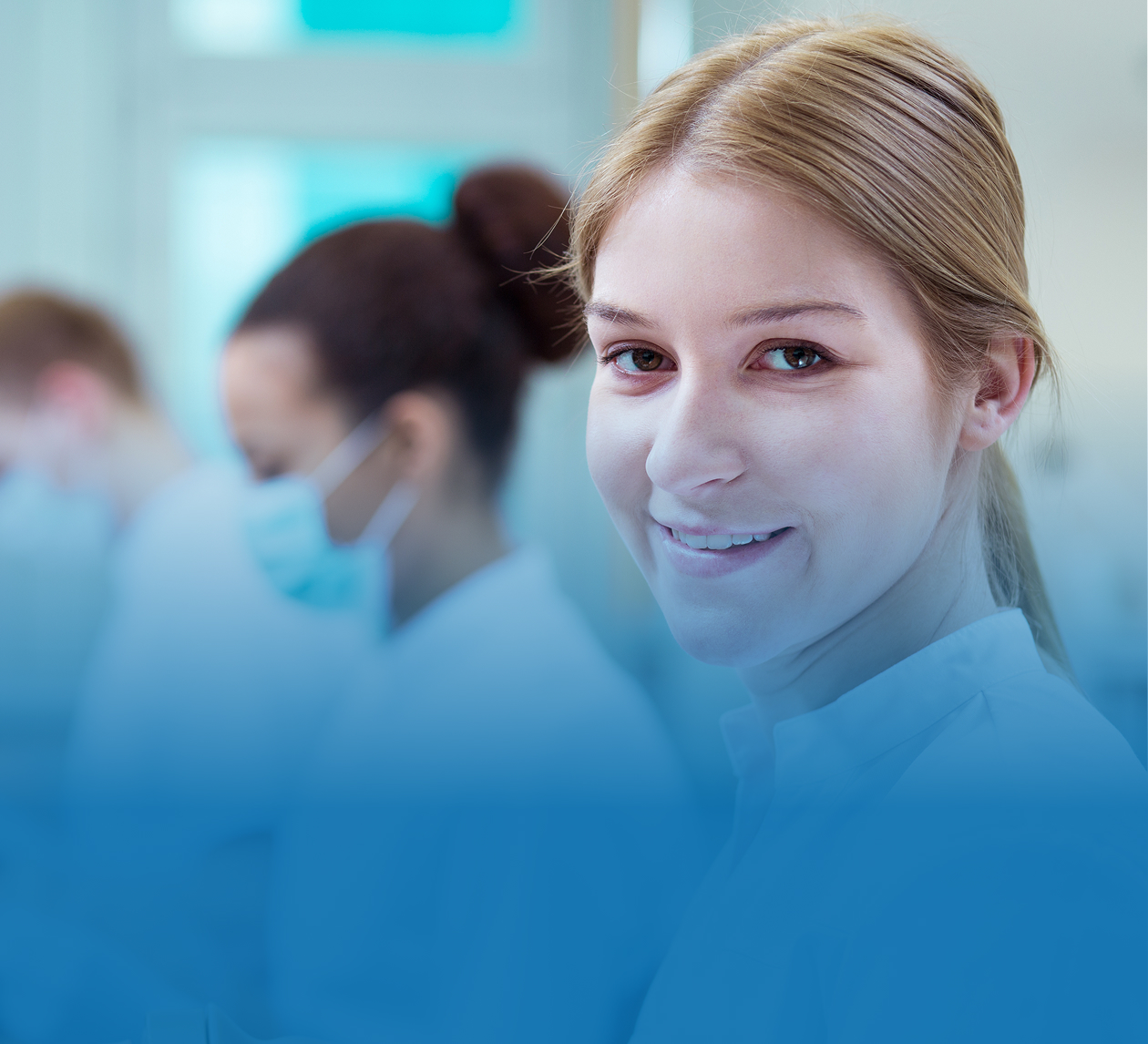 Jeune etudiante en denturologie souriante en clinique, entouree de collegues, illustrant l'adhesion des etudiants a la profession au Quebec.