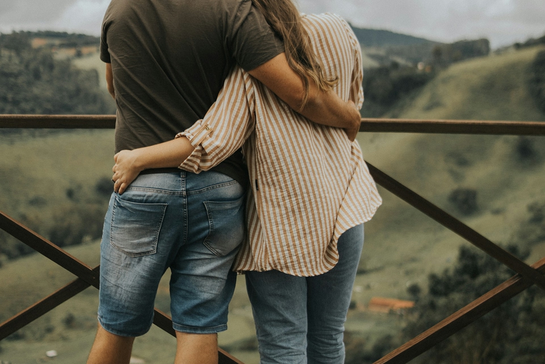 Un couple s'enlace de dos face à un paysage vallonné, symbolisant l'attente et l'espoir vécus durant le parcours d'adoption au Québec.