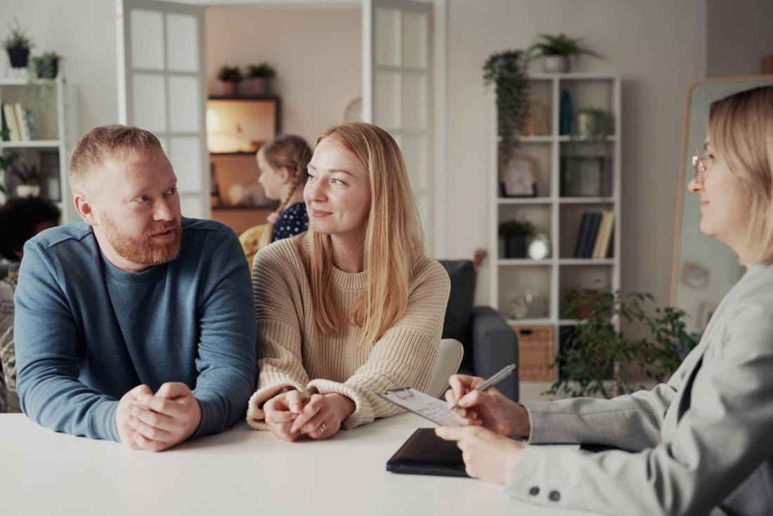Un couple échange avec une conseillère qui prend des notes, dans le cadre d'un accompagnement pour un projet d'adoption au Québec.