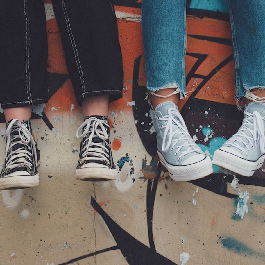 Deux adolescents assis sur un mur graffité, jambes pendantes en baskets, symbole d'un groupe virtuel pour parents d'ados et jeunes adultes au Québec.